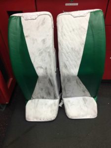 James Reimer green and white Hartford Whalers-themed goalie leg pads displayed upright, showing wear marks from use
