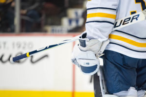 Buffalo Sabres goalie in white jersey holds Bauer stick and blocker during NHL game at Rogers Arena, 2018