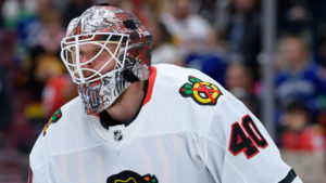 Chicago Blackhawks goalie Robin Lehner in white jersey and decorated mask looks up ice during NHL game