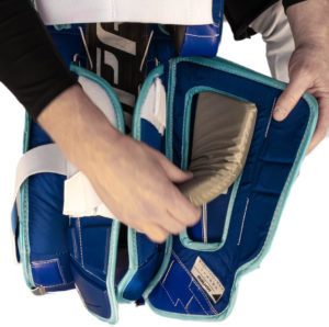 Close-up of goalie leg pad calf pillow attachment being adjusted by hand, blue and teal pads with white strapping