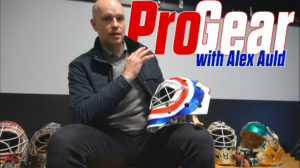 Former NHL goalie Alex Auld holds a goalie mask while surrounded by vintage goalie masks for InGoal Pro Gear review