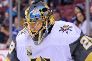 Marc-Andre Fleury in Vegas Golden Knights white jersey and detailed painted goalie mask during NHL game at Rogers Arena
