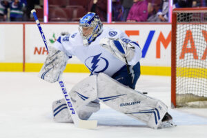 Tampa Bay Lightning goalie makes a glove save in full butterfly, wearing white Bauer gear with Lightning logo at Rogers Ar...