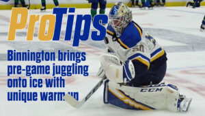 Jordan Binnington in butterfly stance during pre-game warmup, wearing Blues blue and gold gear on ice