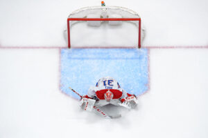 Canadiens goalie in full butterfly stretch makes a save, aerial view showing red pads and white jersey in front of net