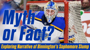 Jordan Binnington in St. Louis Blues gear crouches in his crease, tracking play during an NHL game