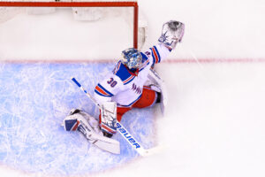 Henrik Lundqvist making a sliding save in full butterfly, Rangers white jersey, overhead view at Rogers Arena crease