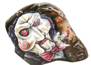 Custom goalie mask painted with Jigsaw character from horror film Saw, featuring red eyes and bow tie airbrush art