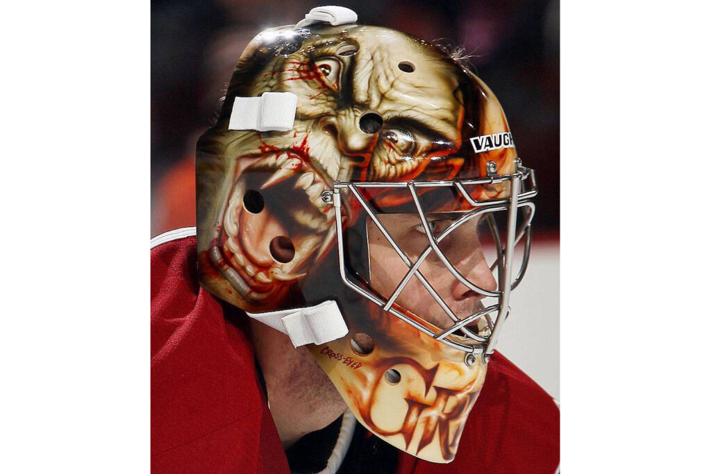 Thomas Greiss goalie mask featuring horror-themed zombie face artwork for Halloween-themed NHL gear feature