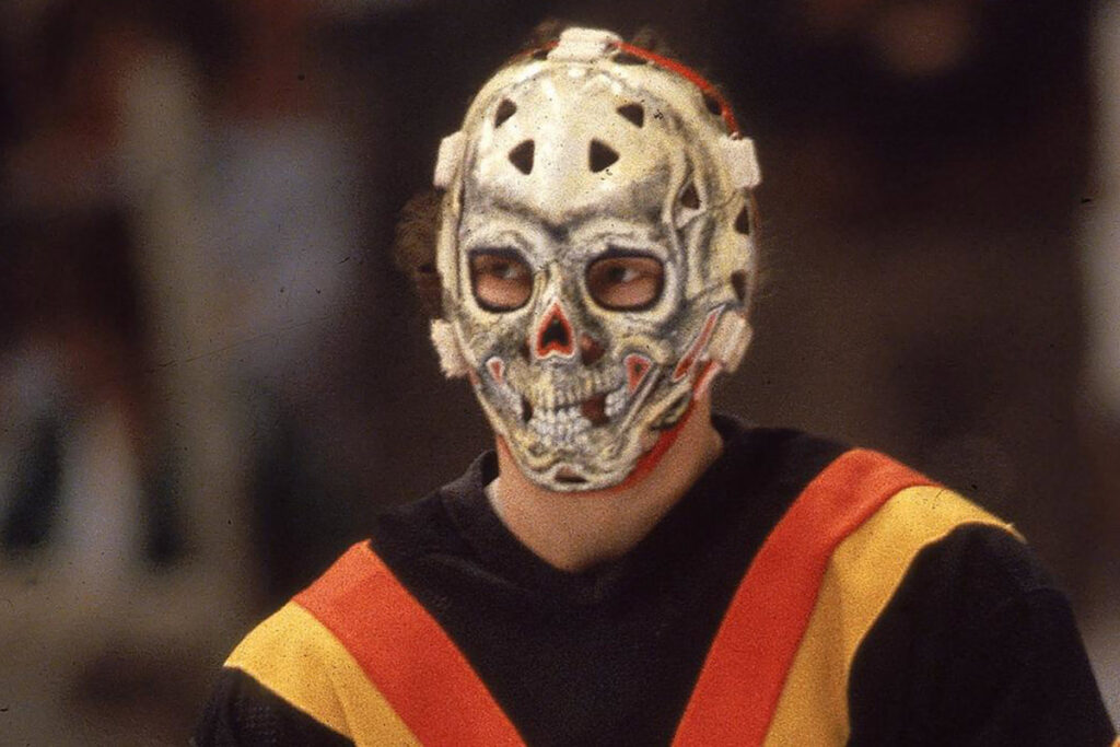 Gary "Suitcase" Smith wearing a skull-painted fiberglass goalie mask in Vancouver Canucks colors during the 1970s NHL era.
