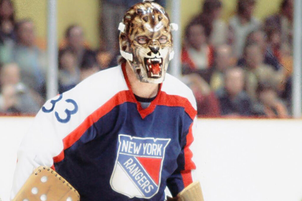 New York Rangers goalie wearing a fierce wolf or bear face Halloween-themed fiberglass mask in vintage NHL game action