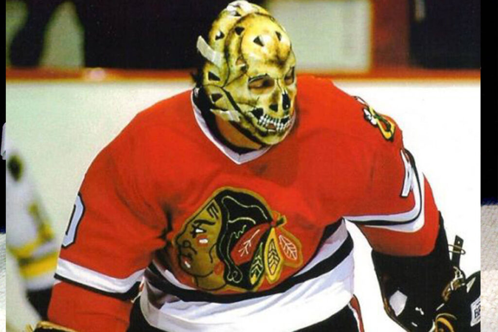 Chicago Blackhawks goalie wearing a skull-painted fiberglass mask in classic red jersey during vintage NHL game
