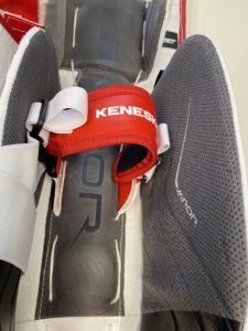 Kenesky goalie pad toe strap in red and white securing a leg pad, close-up detail shot