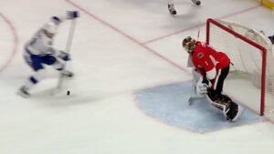 Ottawa Senators goalie Mike Condon in butterfly position making a save attempt on a breakaway, red pads visible near post.