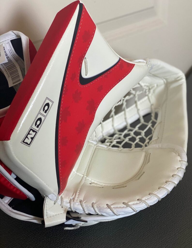 CCM goalie trapper glove in white, red, and navy Team Canada colorway with diamond mesh pocket