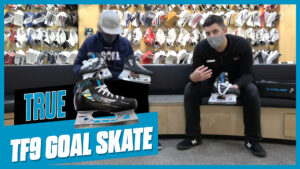 Two men examining True TF9 goalie skates in a hockey shop, one holding the skate for review
