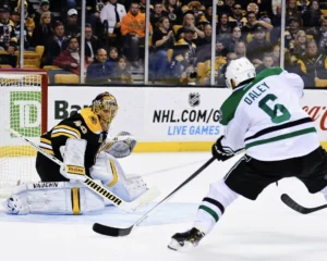Boston Bruins goalie makes a blocker-side save attempt as Stars defenseman Trevor Daley drives to the net at TD Garden