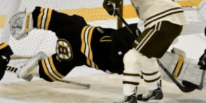 Tuukka Rask dives across crease in full extension making desperation save wearing Boston Bruins black and gold pads