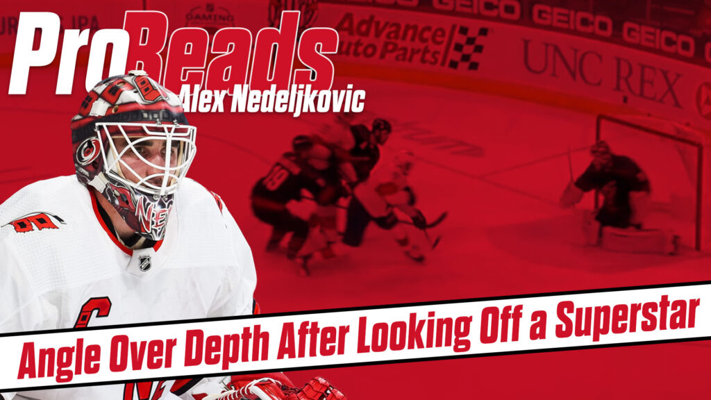 Alex Nedeljkovic in red Carolina Hurricanes gear in butterfly position making a save during an NHL game