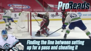 Joey Daccord in Kraken green pads butterflies across crease tracking a cross-ice pass threat during NHL game action