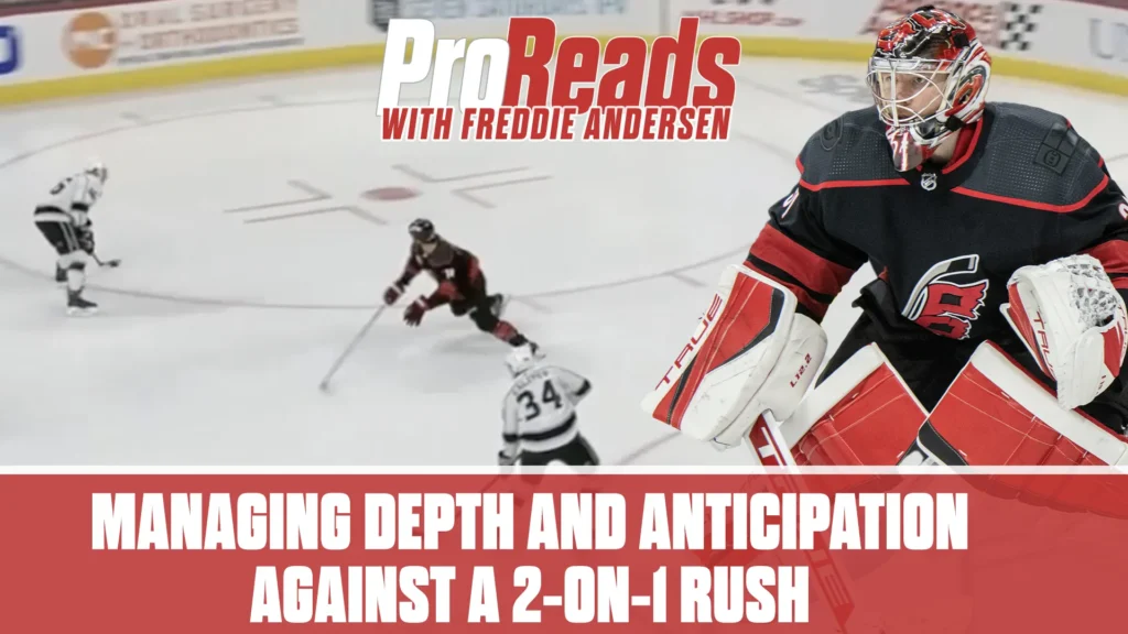 Freddie Andersen in Hurricanes red gear squares up in his crease, tracking a 2-on-1 rush during an NHL game.