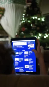 Person browsing InGoal Magazine on a tablet beside a lit Christmas tree, perfect holiday gift for hockey goalies