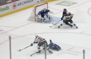 Thatcher Demko in RVH position hugging the post as a Wild skater drives toward the net on a rush play.