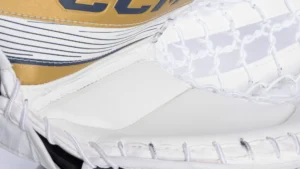 Close-up of CCM Eflex 6 goalie glove showing white and gold colorway with textured palm and finger protection