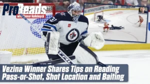 Connor Hellebuyck in Winnipeg Jets gear in his crease, tracking a 2-on-1 rush in butterfly-ready stance, blocker visible