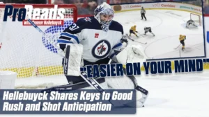 Connor Hellebuyck in Winnipeg Jets white pads in butterfly stance tracking a rush, glove up, ready to square to shooter