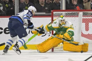 Marc-Andre Fleury makes a pad save in Minnesota Wild yellow-green pads as Jets forward cuts to the crease during Fleury's ...