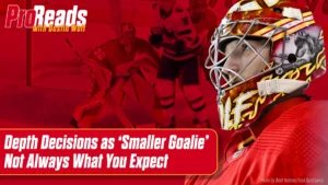 Dustin Wolf Calgary Flames goalie in red mask making a flash screen save, glove up in butterfly position