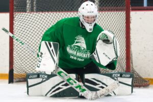 Young goalie Matty in green Minor Hockey jersey making a butterfly save in CCM pads during practice