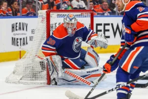 Calvin Pickard in RVH position protecting the post in Oilers blue pads, tracking a puck in tight during an NHL game.