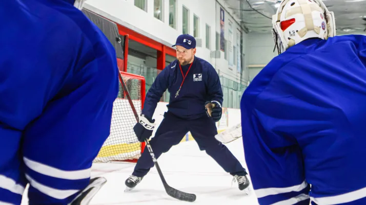 Goalie coach at Connecticut Crease leads on-ice training drill, demonstrating stick positioning to young goaltenders at No...