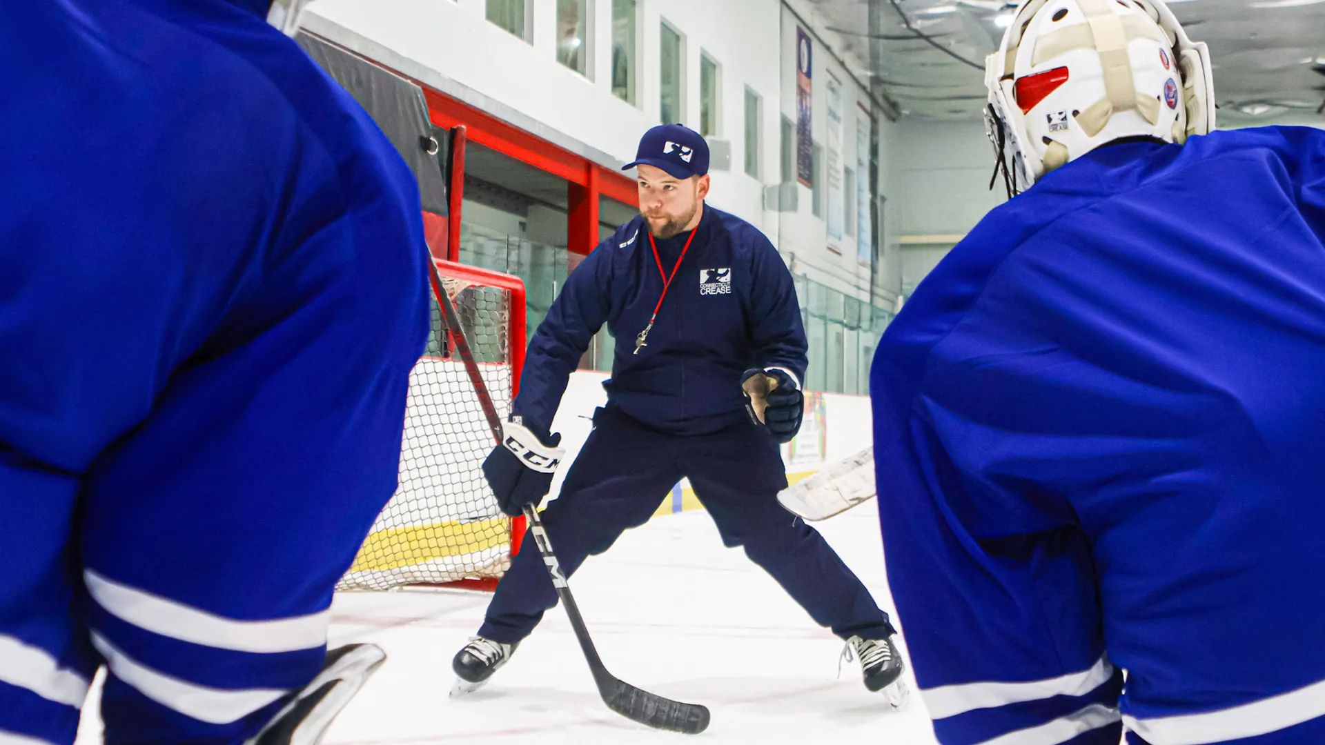 Goalie coach at Connecticut Crease leads on-ice training drill, demonstrating stick positioning to young goaltenders at No...