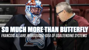 Colorado Avalanche goalie in colorful mask talks with goaltending coach François Allaire during a stoppage in play.