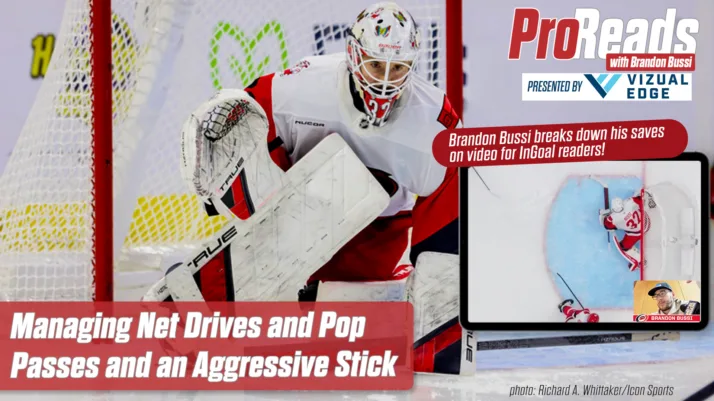 Brandon Bussi makes a paddle-down save in white Detroit Red Wings gear, aggressively challenging with his stick extended.