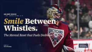Ann-Renée Desbiens in PWHL Montreal red jersey smiling during stoppage, wearing full goalie gear including mask and blocker
