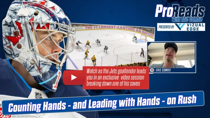 Jets goalie Eric Comrie in white mask with red maple leaf tracks a rush during a ProReads video breakdown session