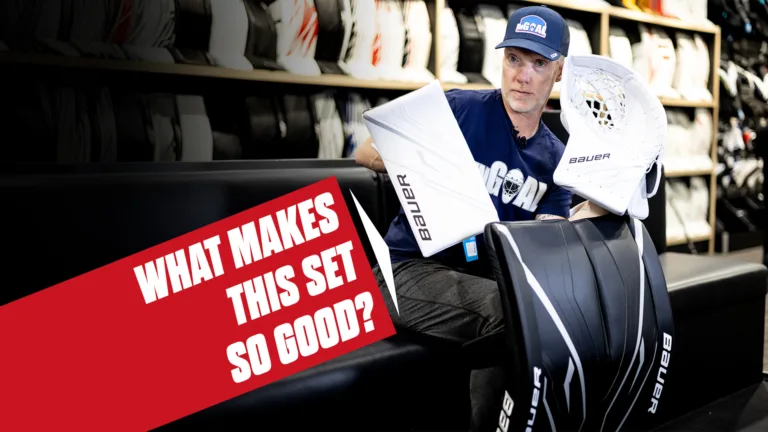 Goalie holding Bauer GSX leg pads and gloves in equipment room with gear shelves in background